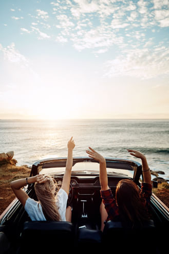 Couple of friends taking a road trip and enjoying their vacation soaking in sea views