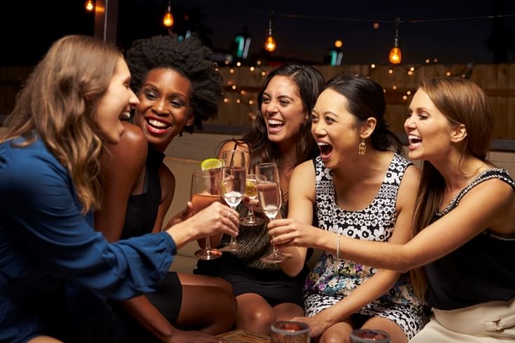 Group of happy friends enjoying drinks and dinner at a luxury hotel